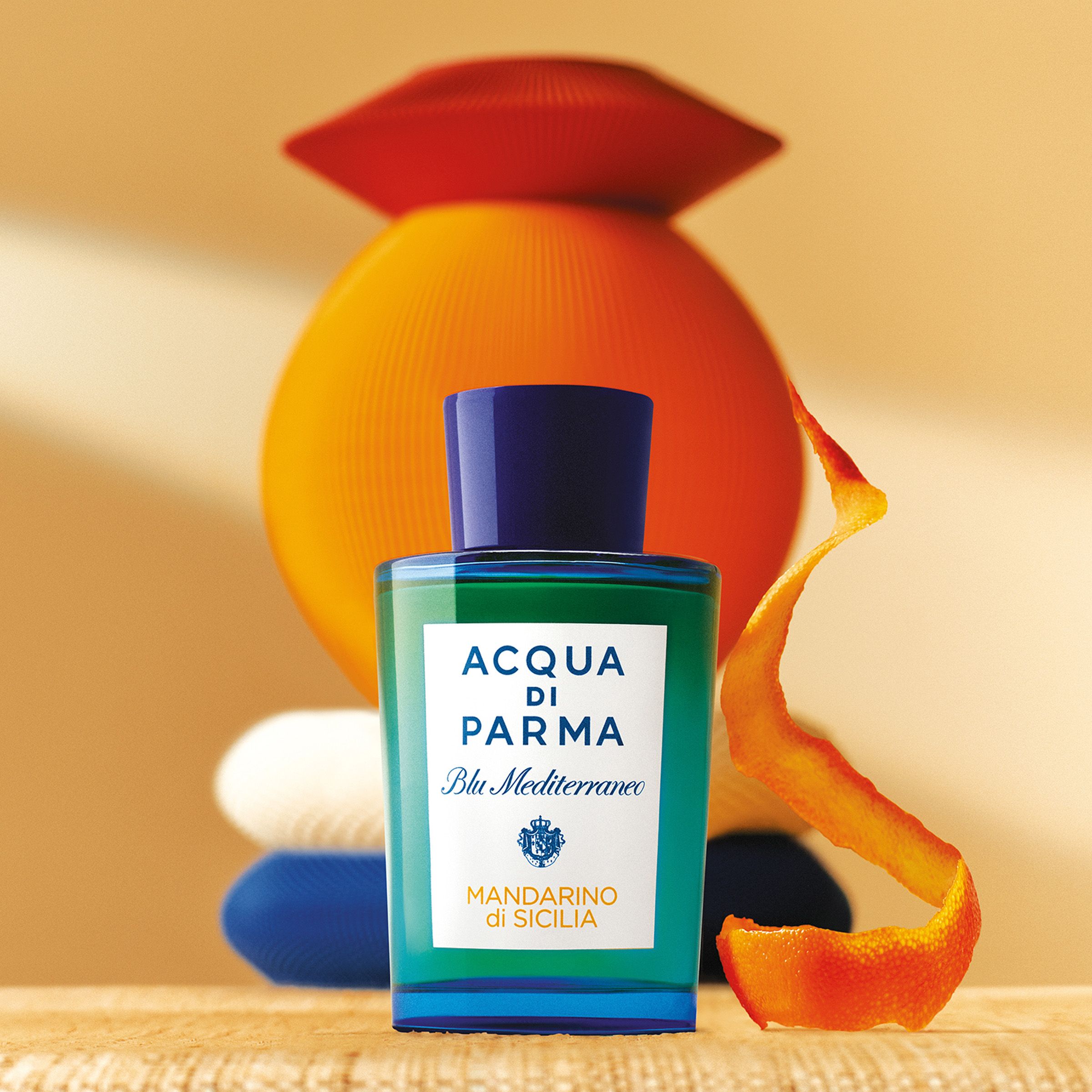 Acqua Di Parma fragance multishape objects behind it, and a orange peel placed on the side