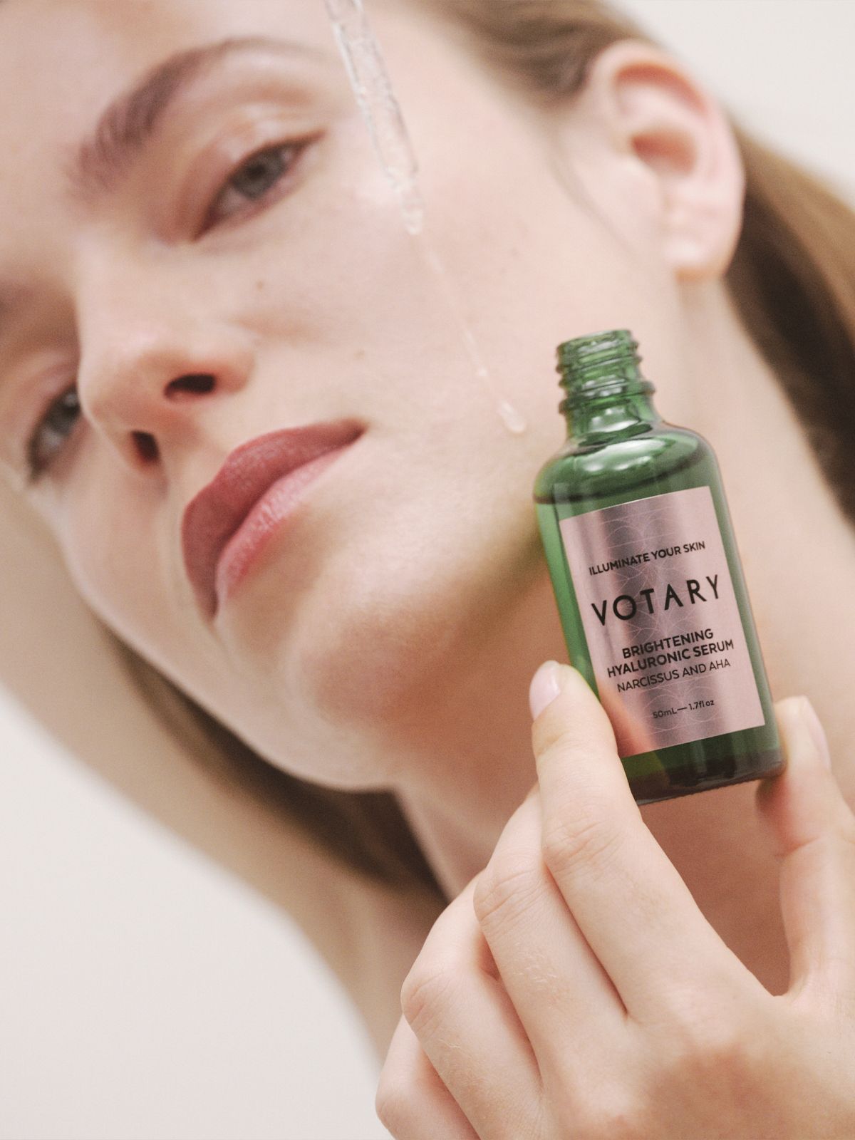 Image of a woman dripping Votary product on her face