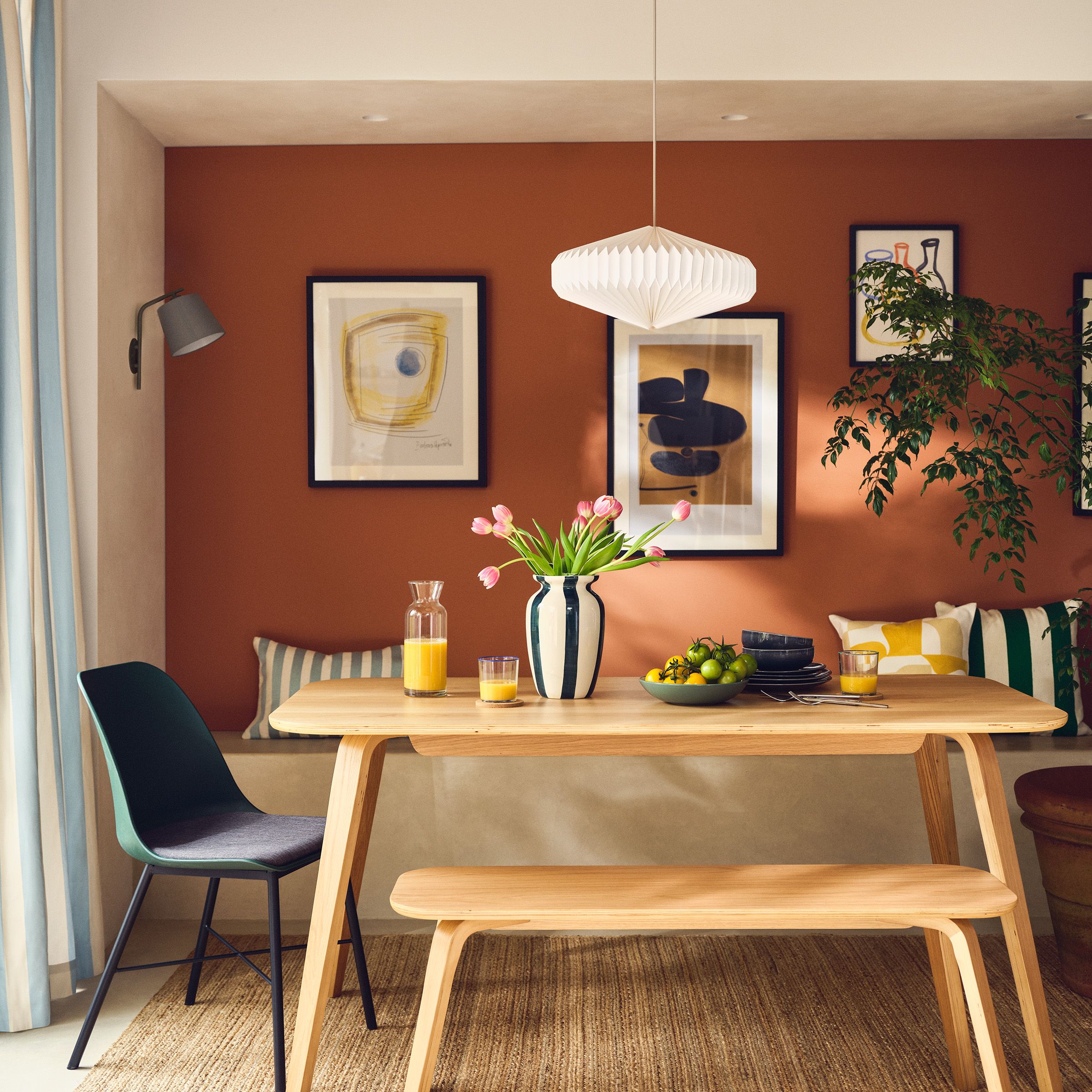 Framed artwork above a dining table against an orange wall