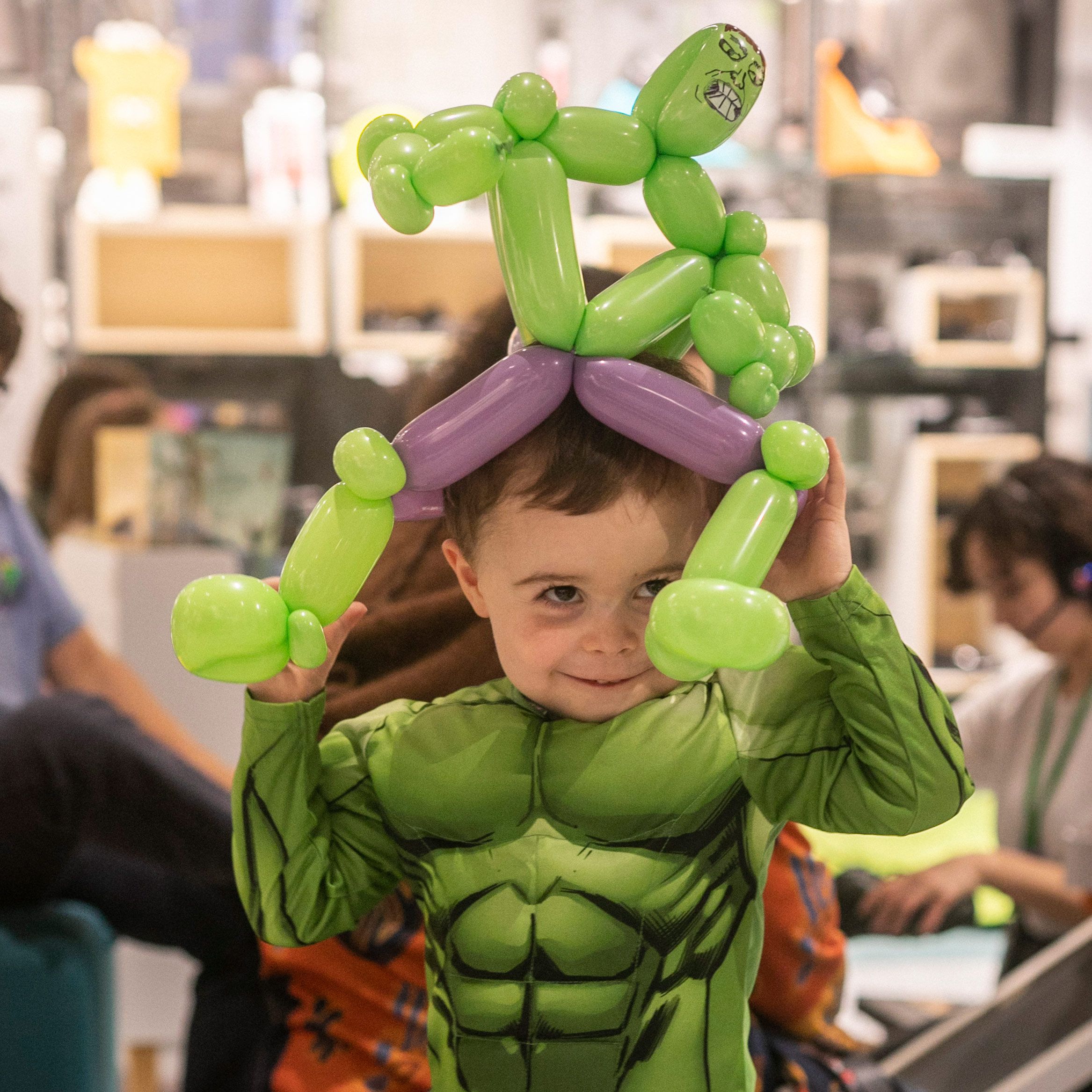 a boy dressed as the incredible hulk holding an incredible hulk balloon