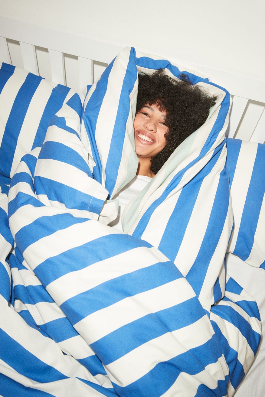 Image of a student wrapped up in a stripy duvet