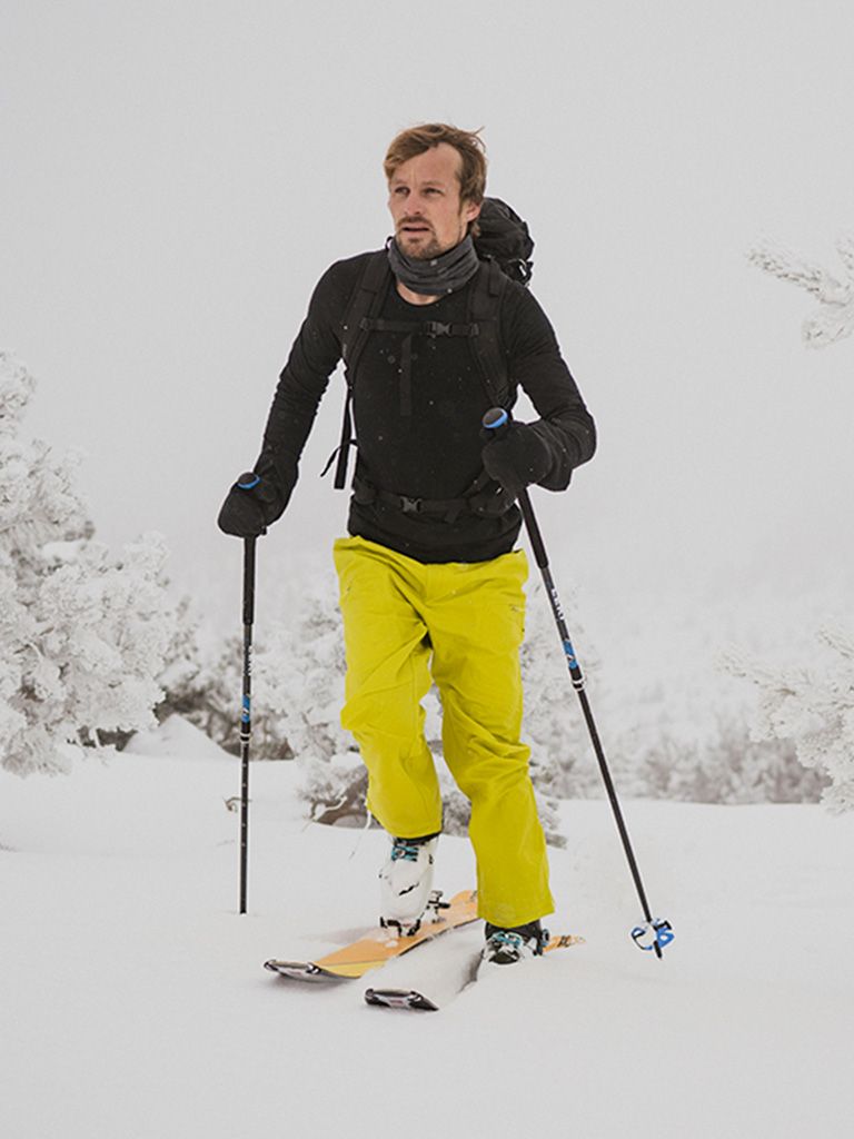 Man on skiis in Icebreaker black long sleeved top and yellow ski trousers