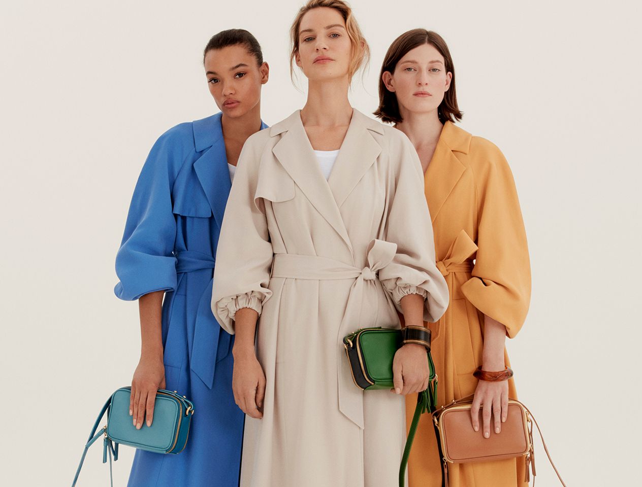 Models wearing blue, yellow and stone trench coats