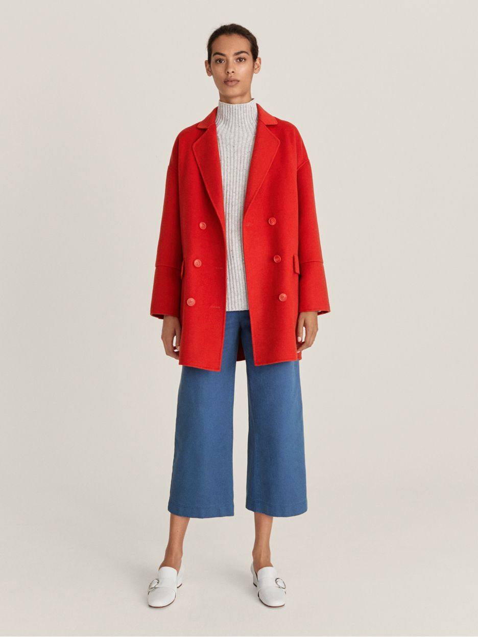 Model wearing red coat and blue wide-leg cropped trousers