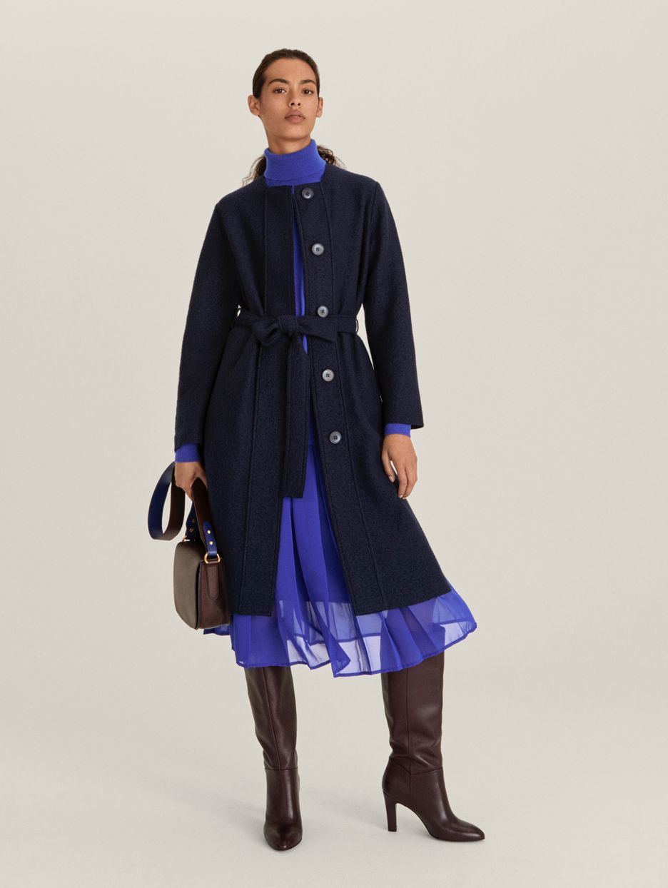 Model wearing blue coat and pleated sheer skirt