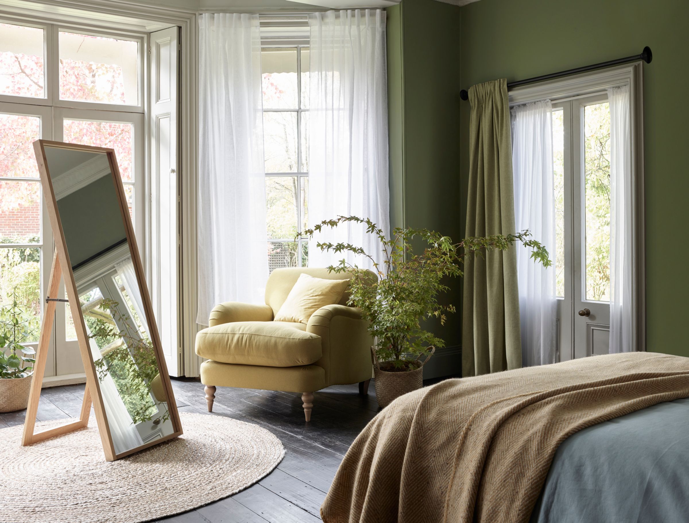 Green bedroom with wood frame mirror