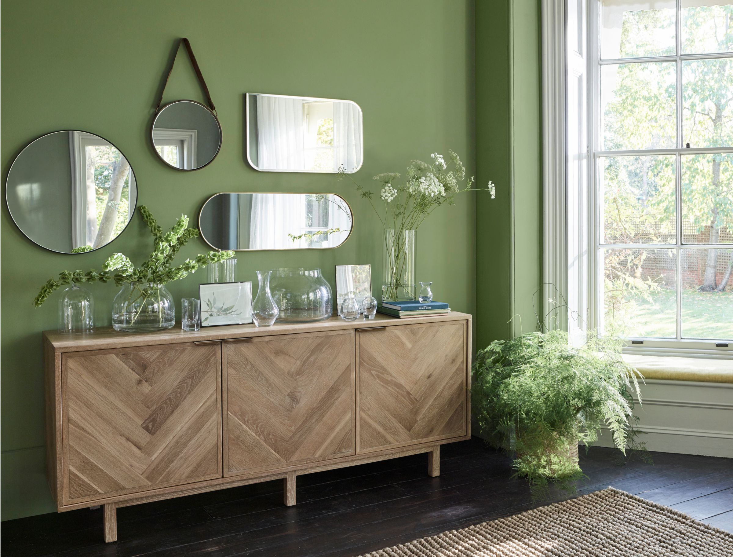 Green wall with mirrors and wooden cabinet