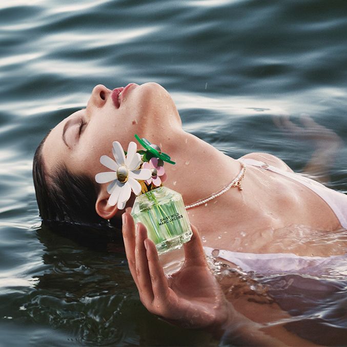 women floating in a lake holding a bottle of Marc Jacobs Daisy Wild Eau de Parfum
