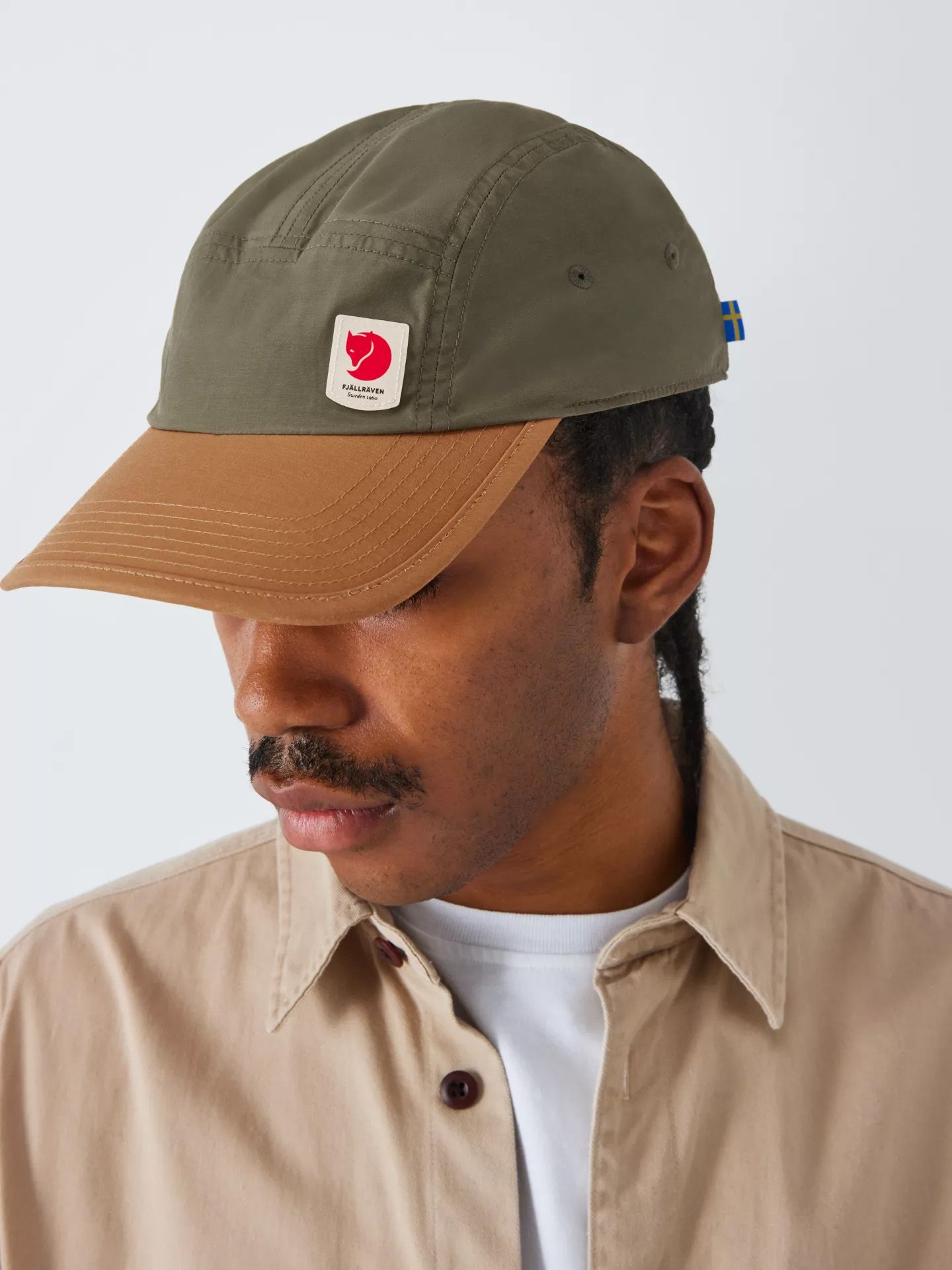 Man wearing a khaki Fjallraven cap