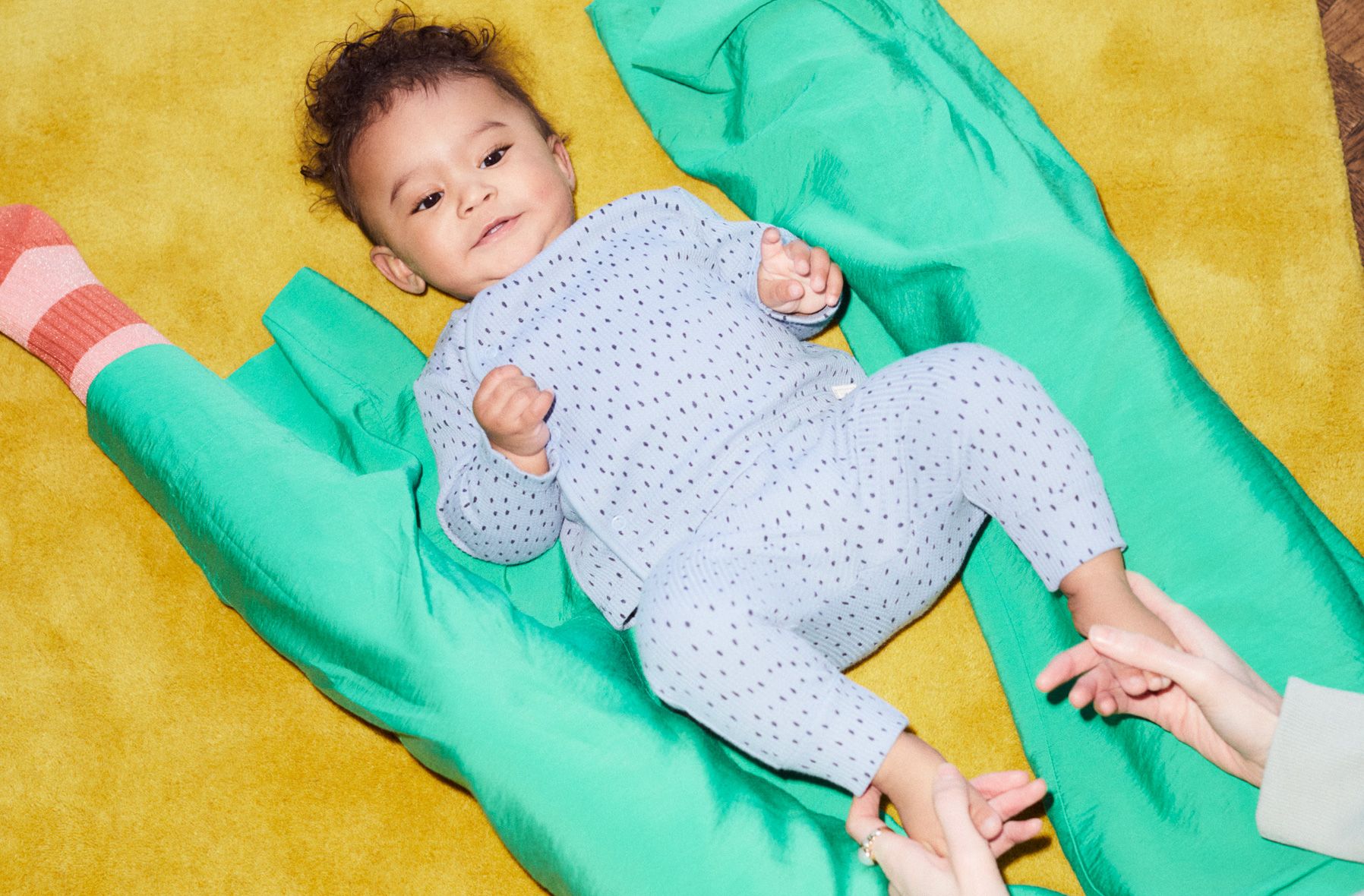 Image of a baby lying on the floor inbetweens it's mothers legs