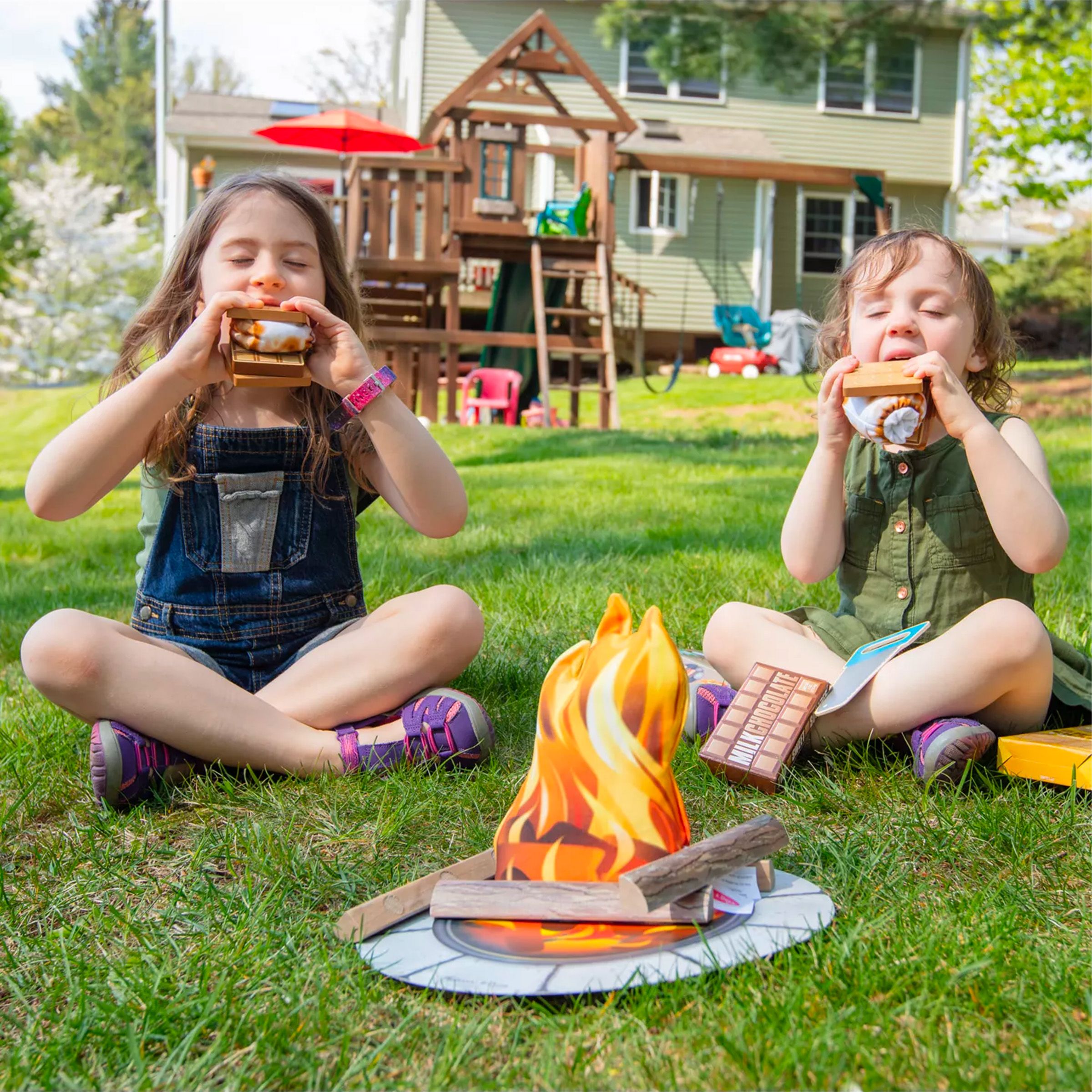 two girls in there garden eating smores around a pretend fire