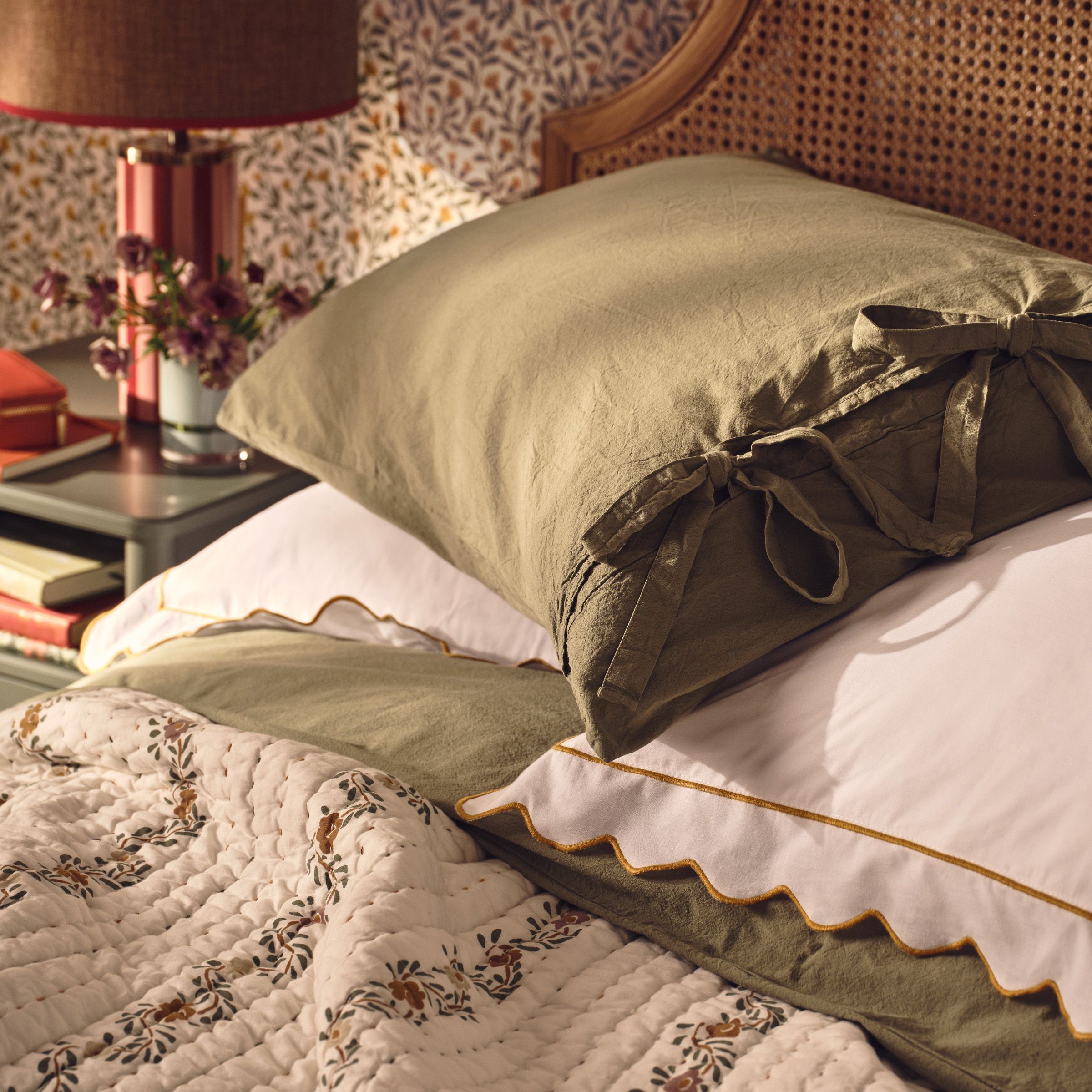 Close up image of a bed with a throw and scatter cushions on the bed