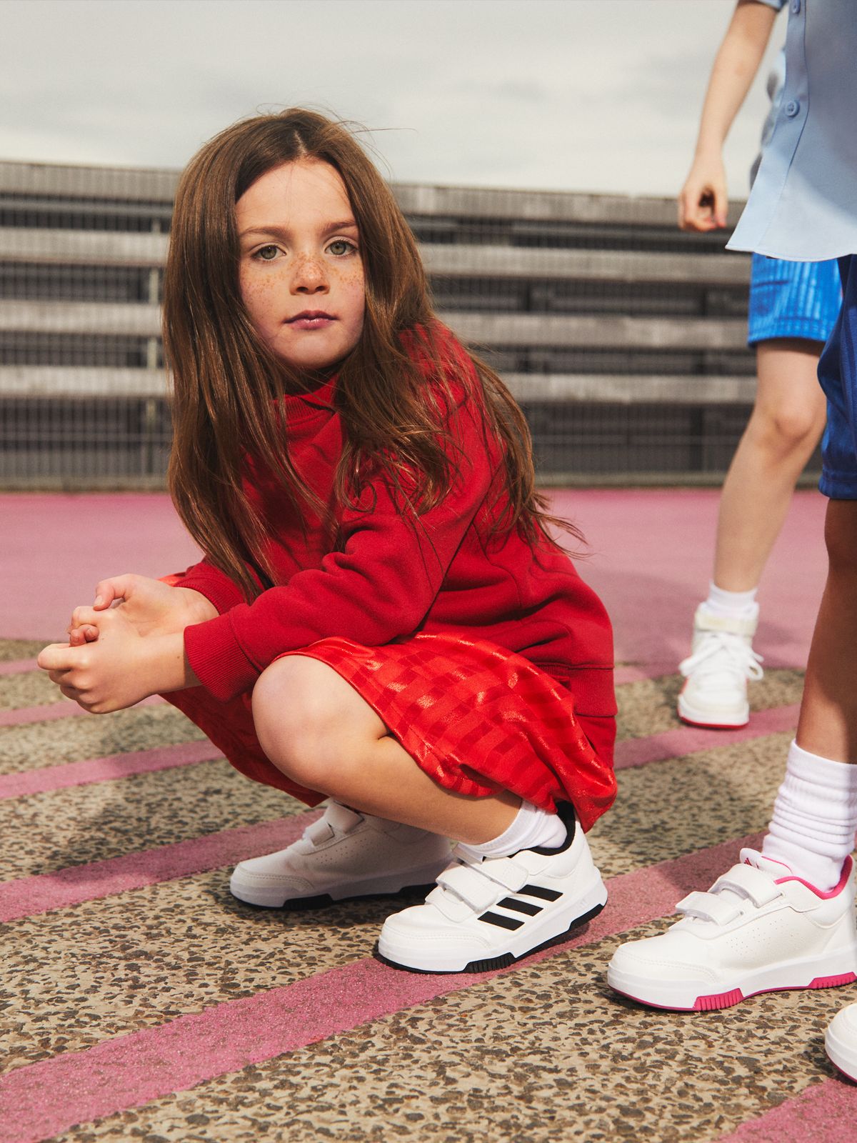 Image of a girl crouching down wearing red shorts and trainers