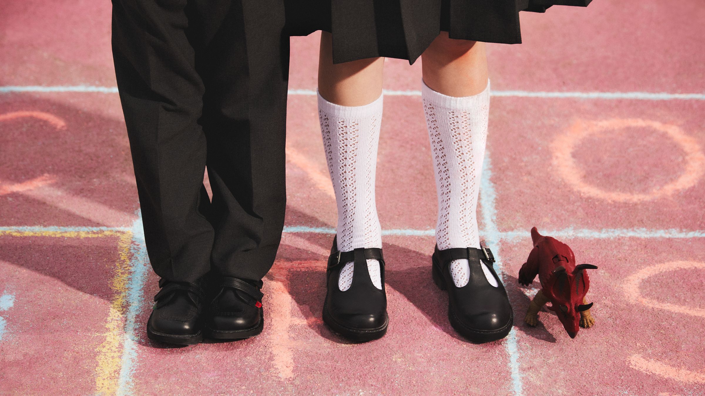 Close up image of two people wearing school shoes on the playground