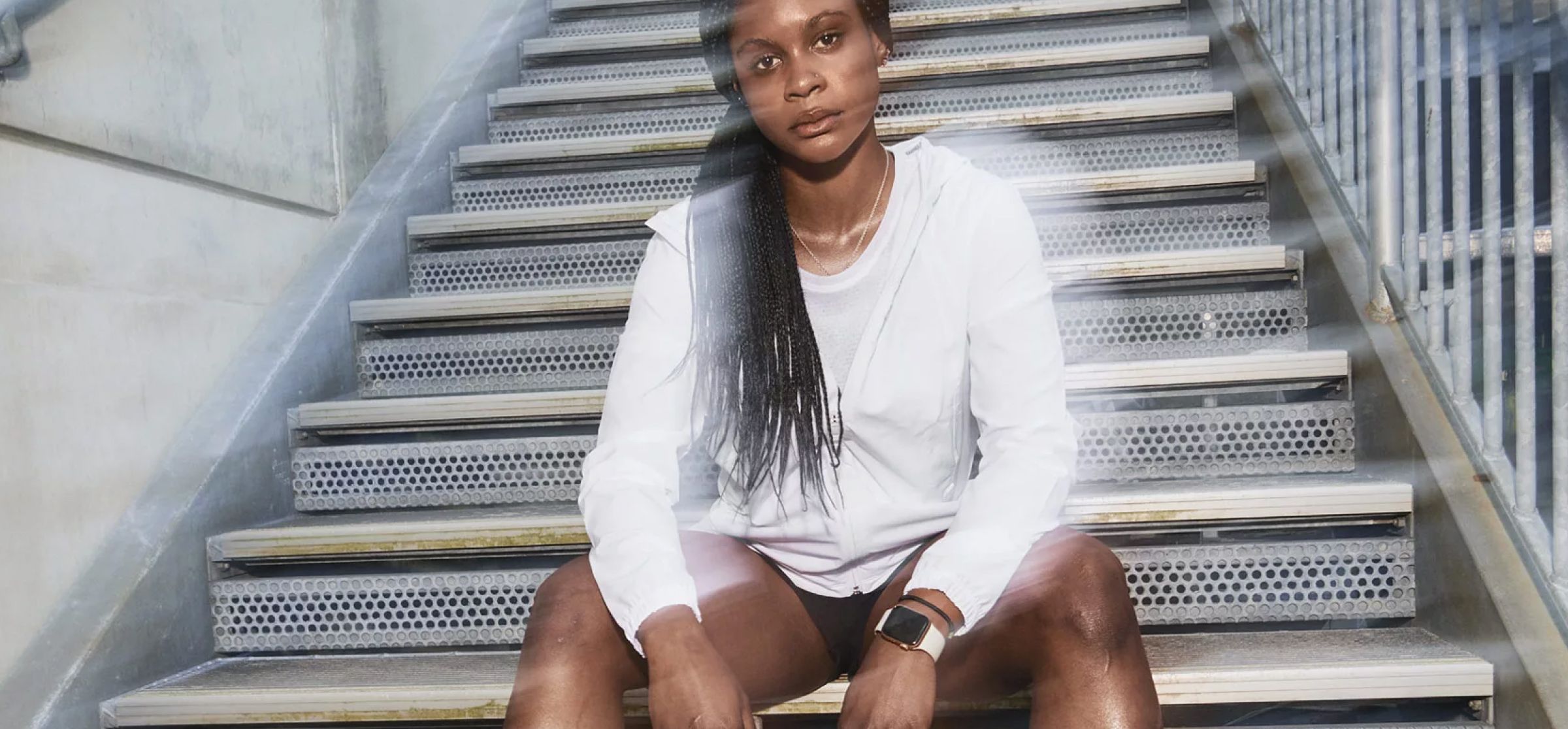 Image of an woman sitting on some outside steps wearing Under Armour