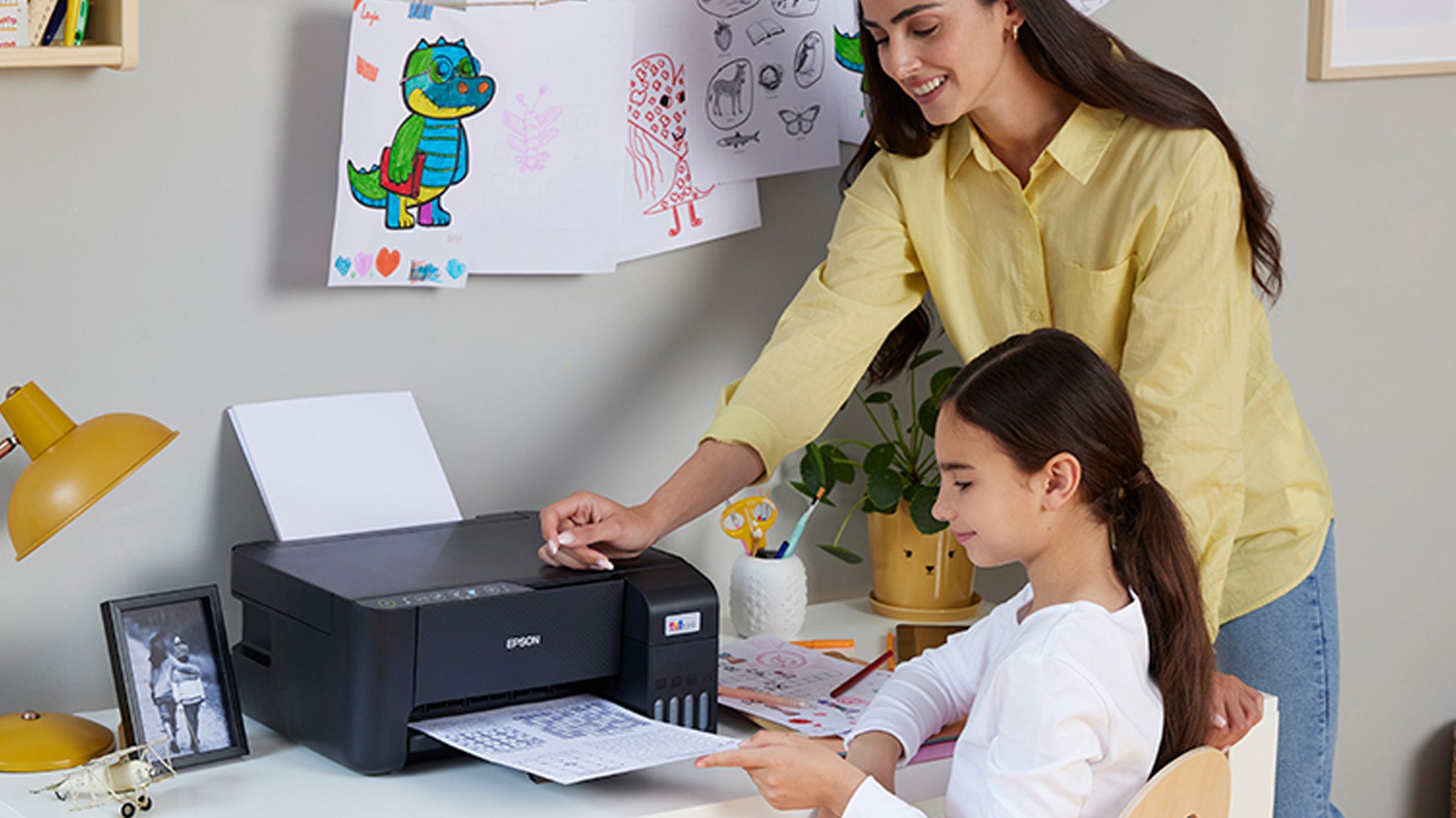 Mother and daughter smiling using a printer on a desk at home
