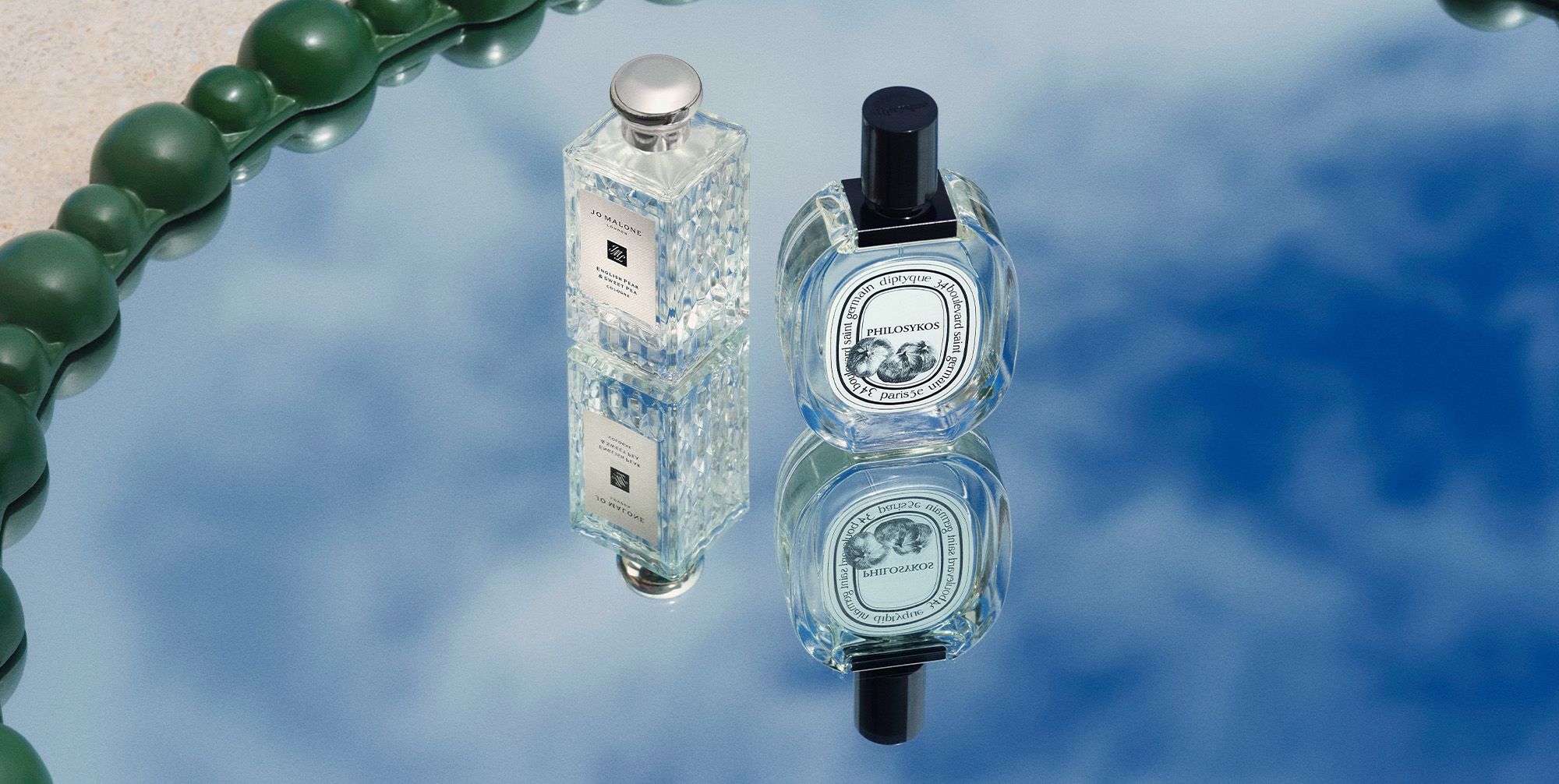Bottles of frangrances sitting on a mirror reflecting a blue sky