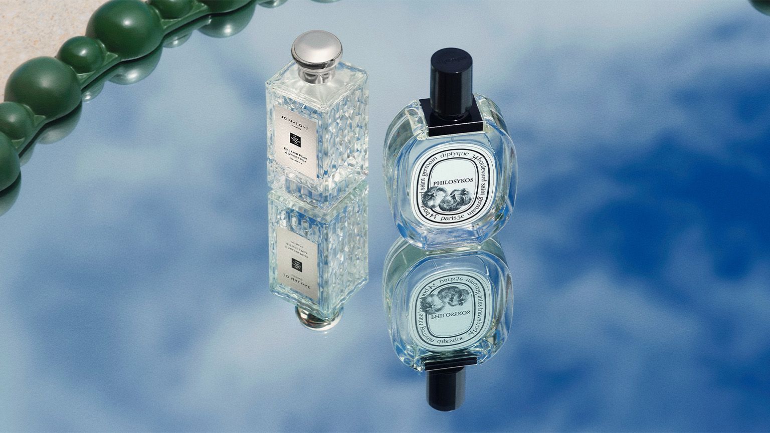 Fragrances sitting on a mirrow reflecting the sky