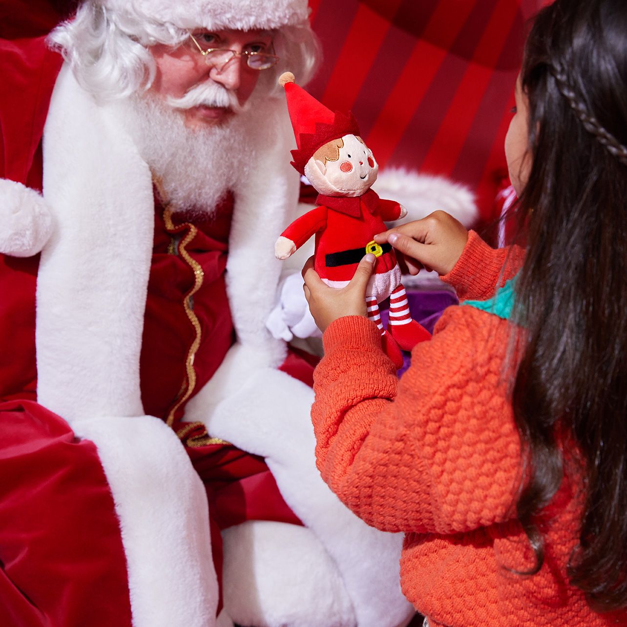 Image of a Santa showing a child a elf toy