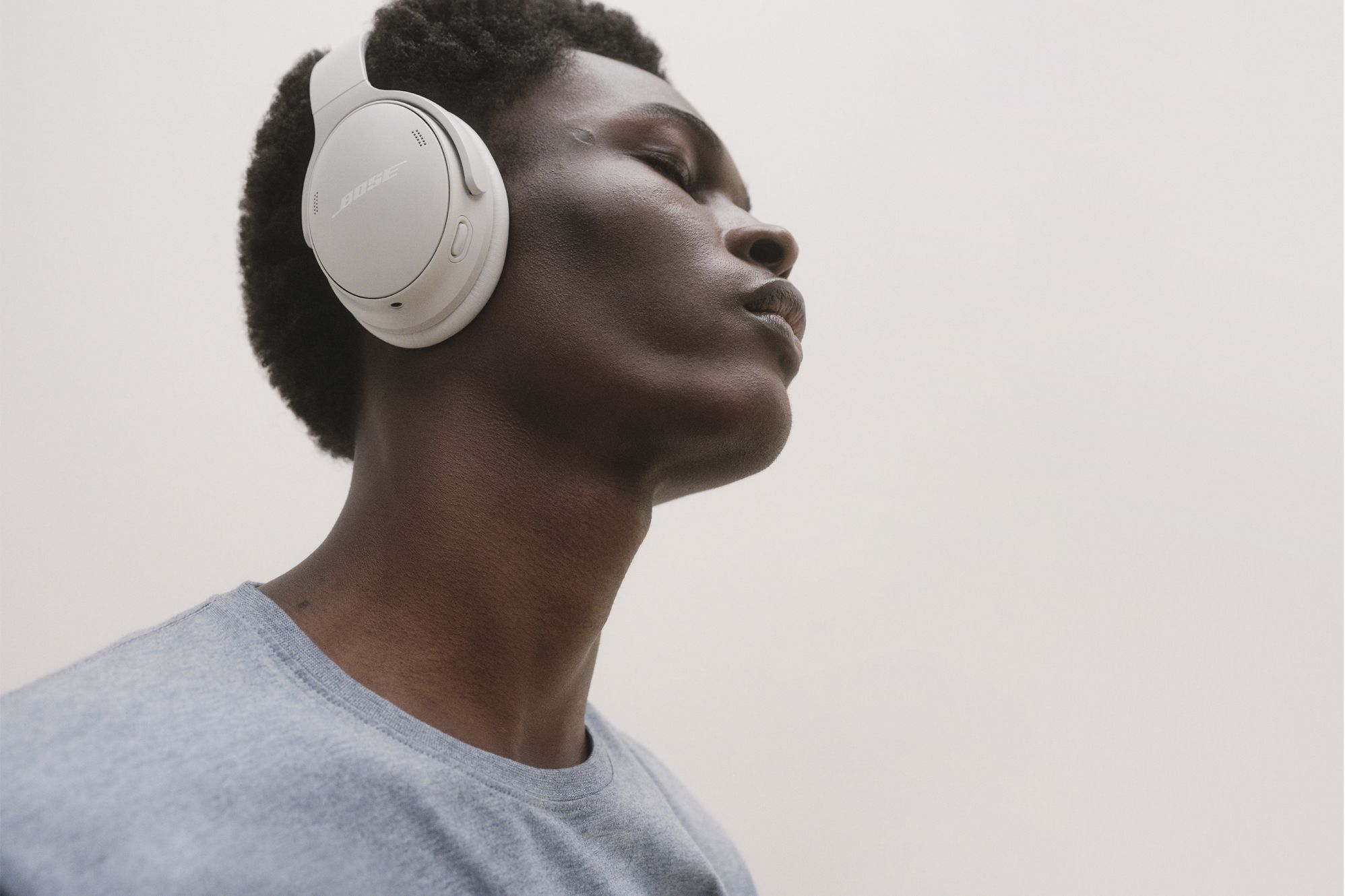 Image of a man hearing beige Bose headphones