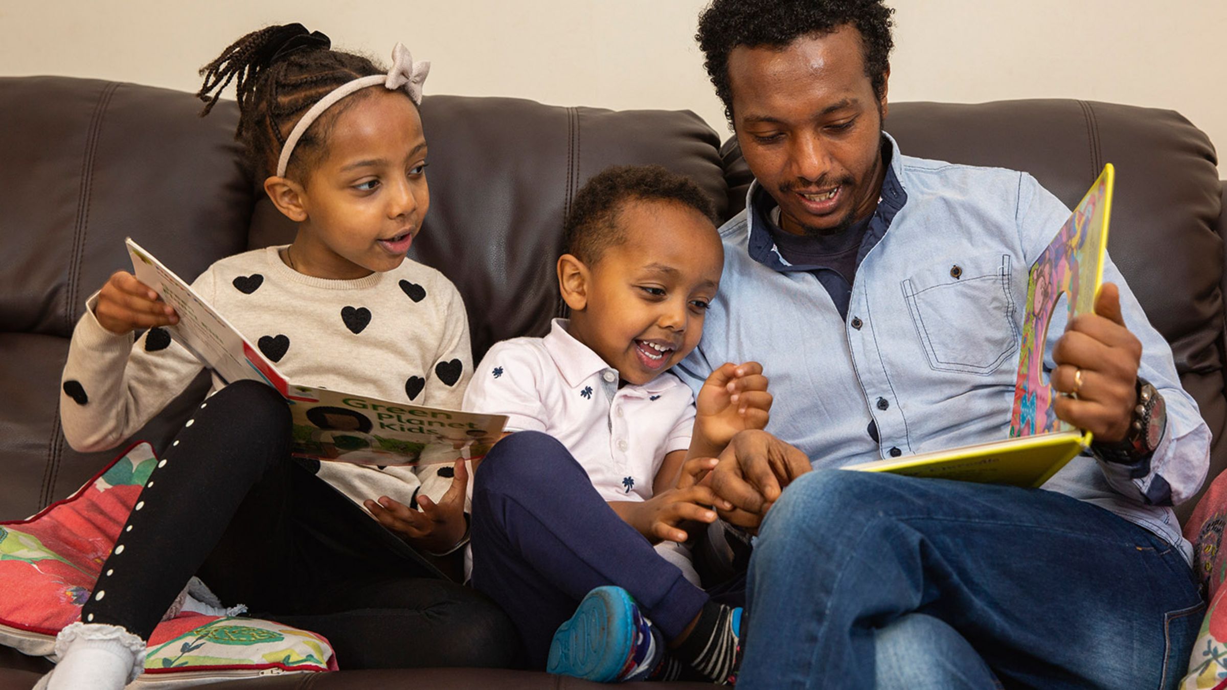  Give a Little Love - Father and children on sofa reading childrens books