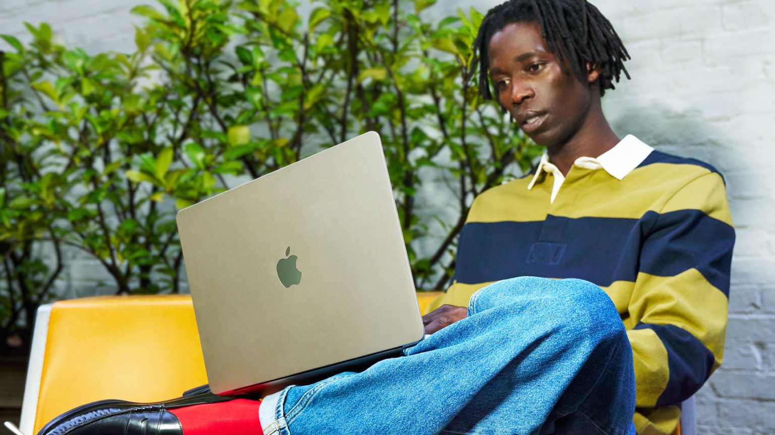 Man seated holding a MacBook Air on his lap