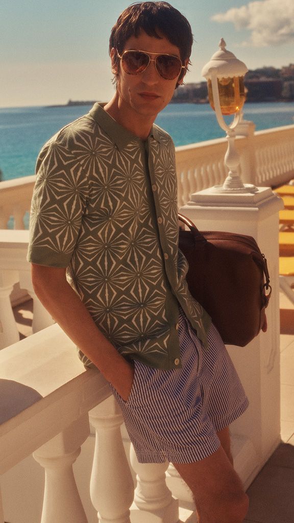 Man in sunglasses and green shirt leaning against a balcony on holiday