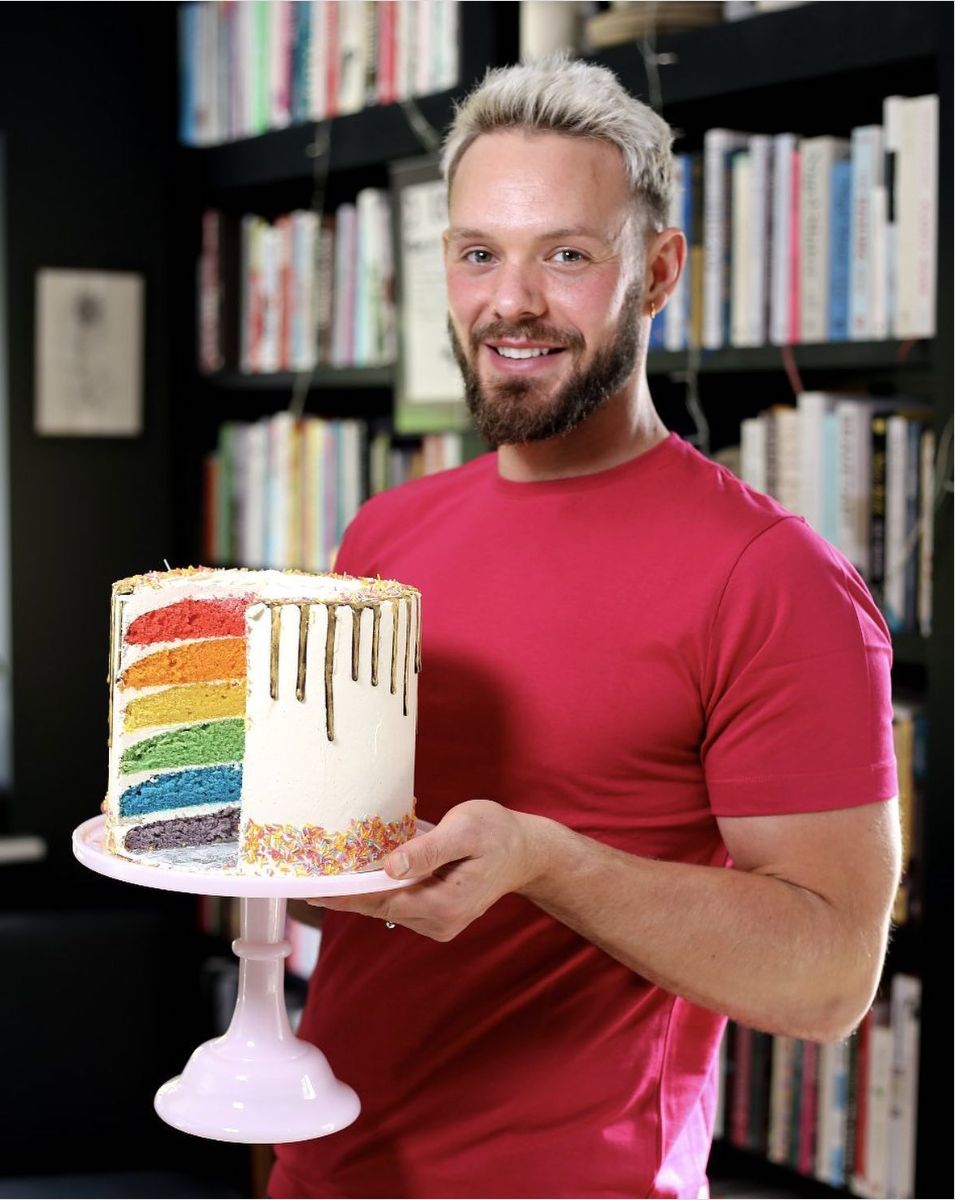 Image of John Whaite holding the Rainbow cake