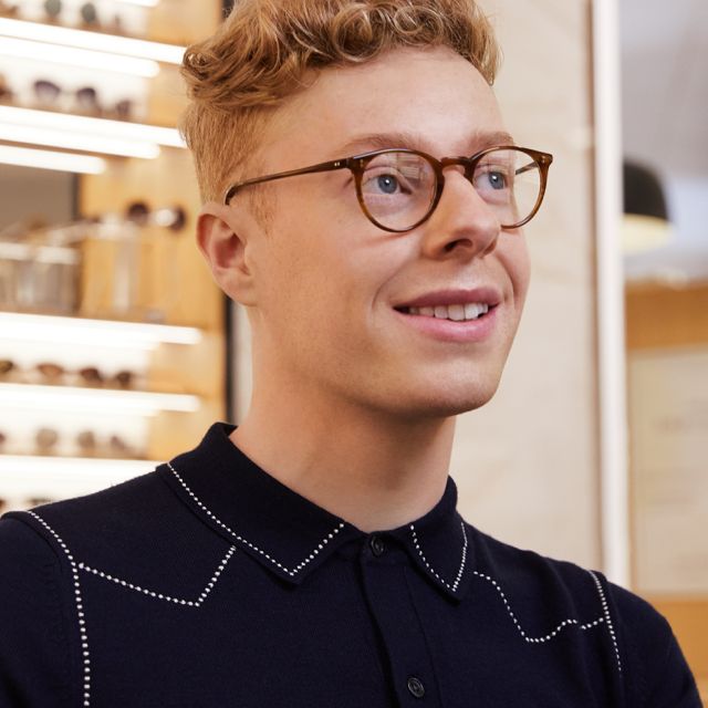 man standing in an opticians wearing glasses