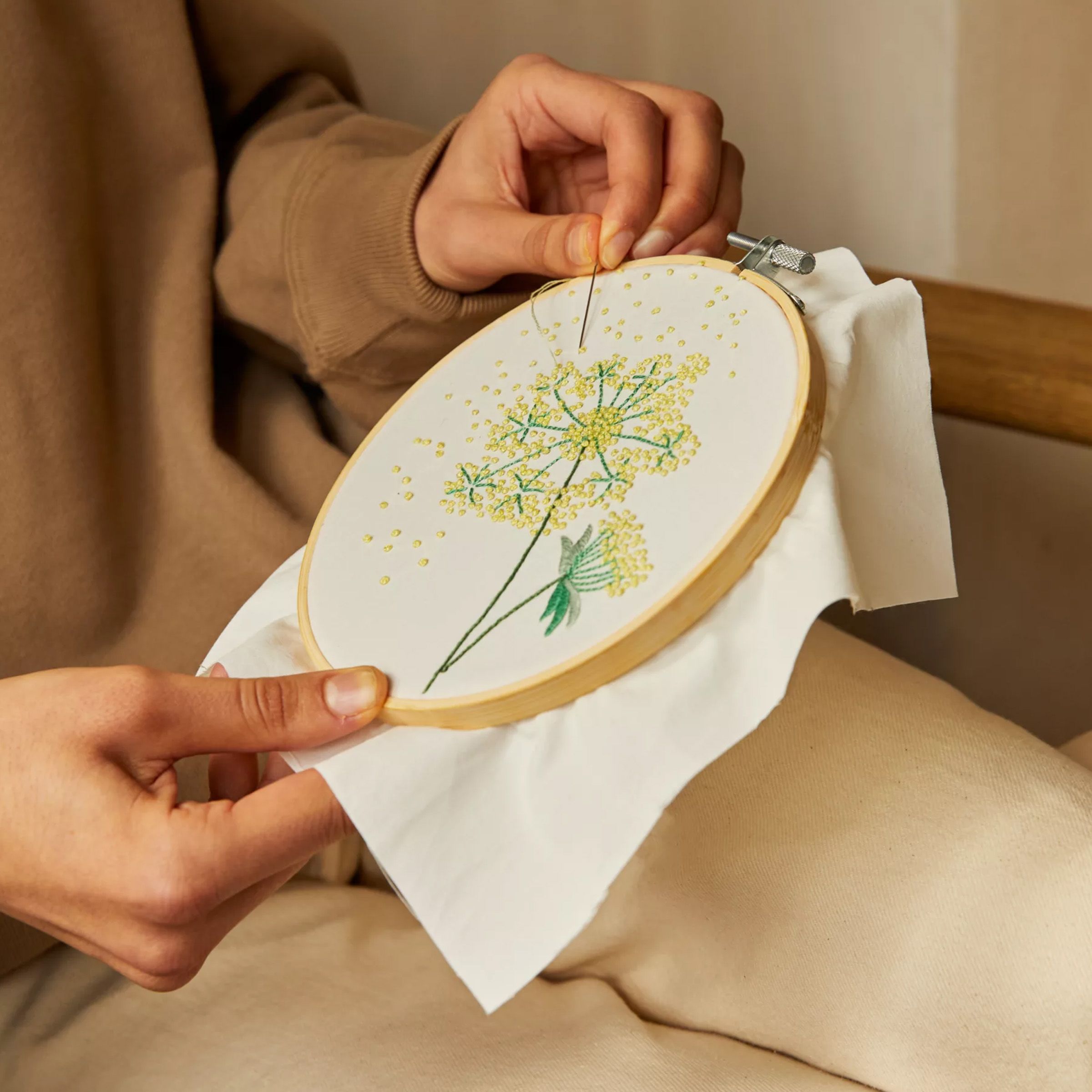 Person embroidering a flower onto a piece of fabric