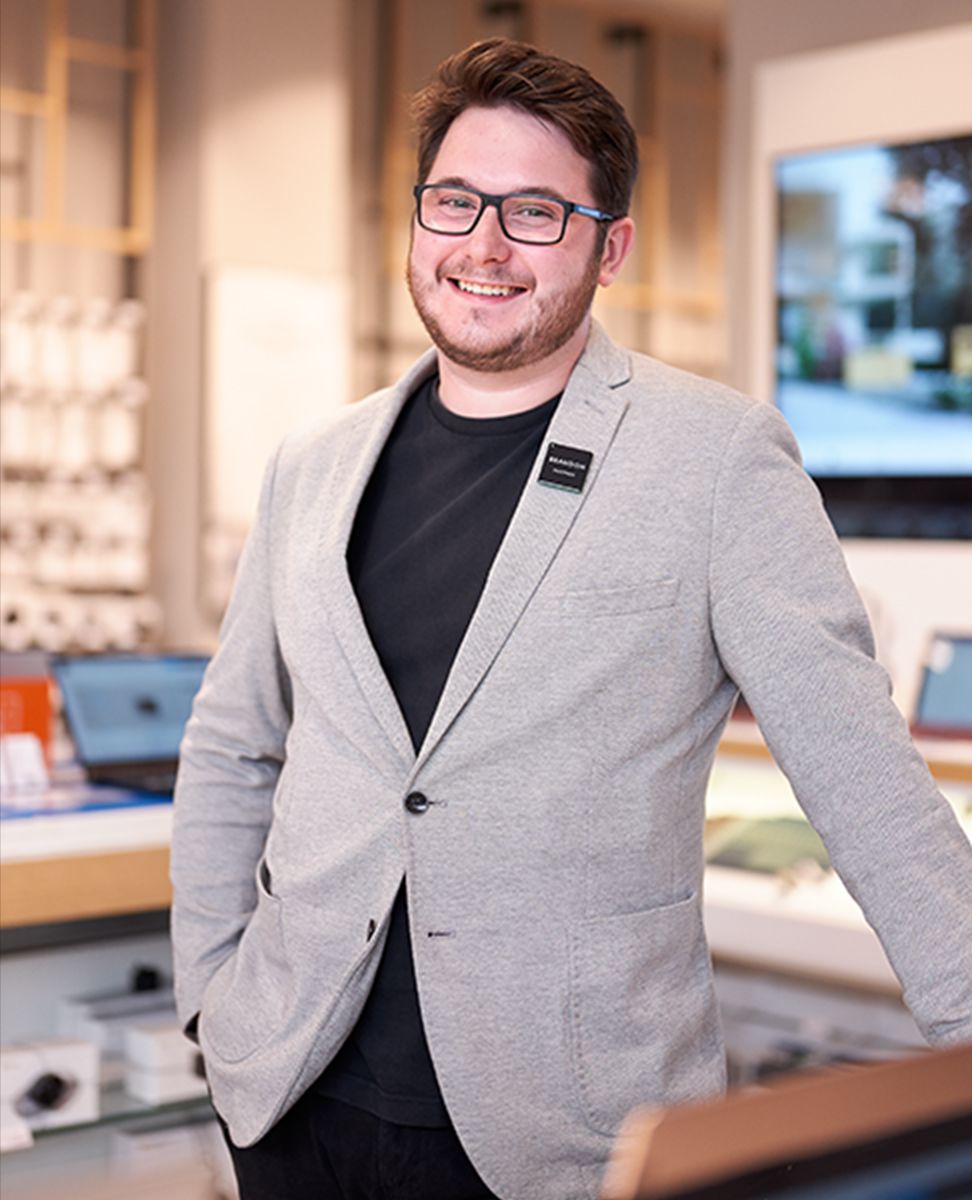 Employee portrait image, standing among products in an in-store Technology department 