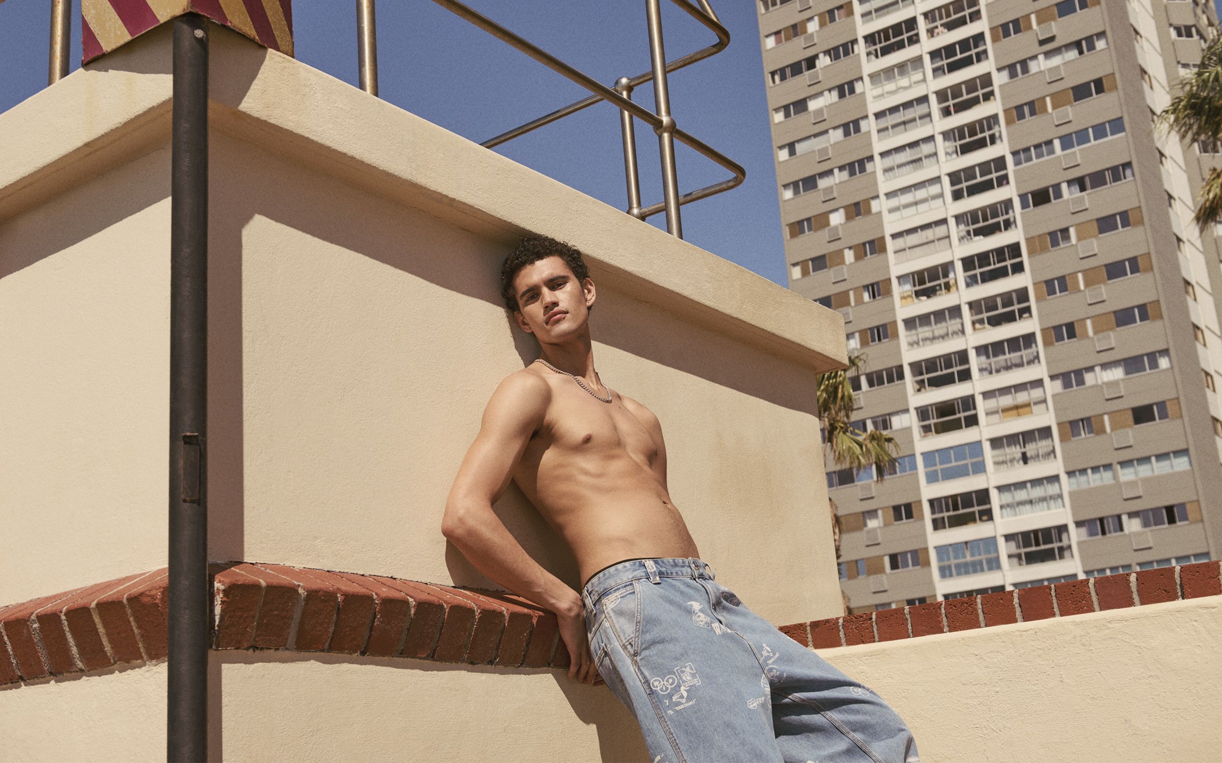 Image of a topless man leaning up against a wall