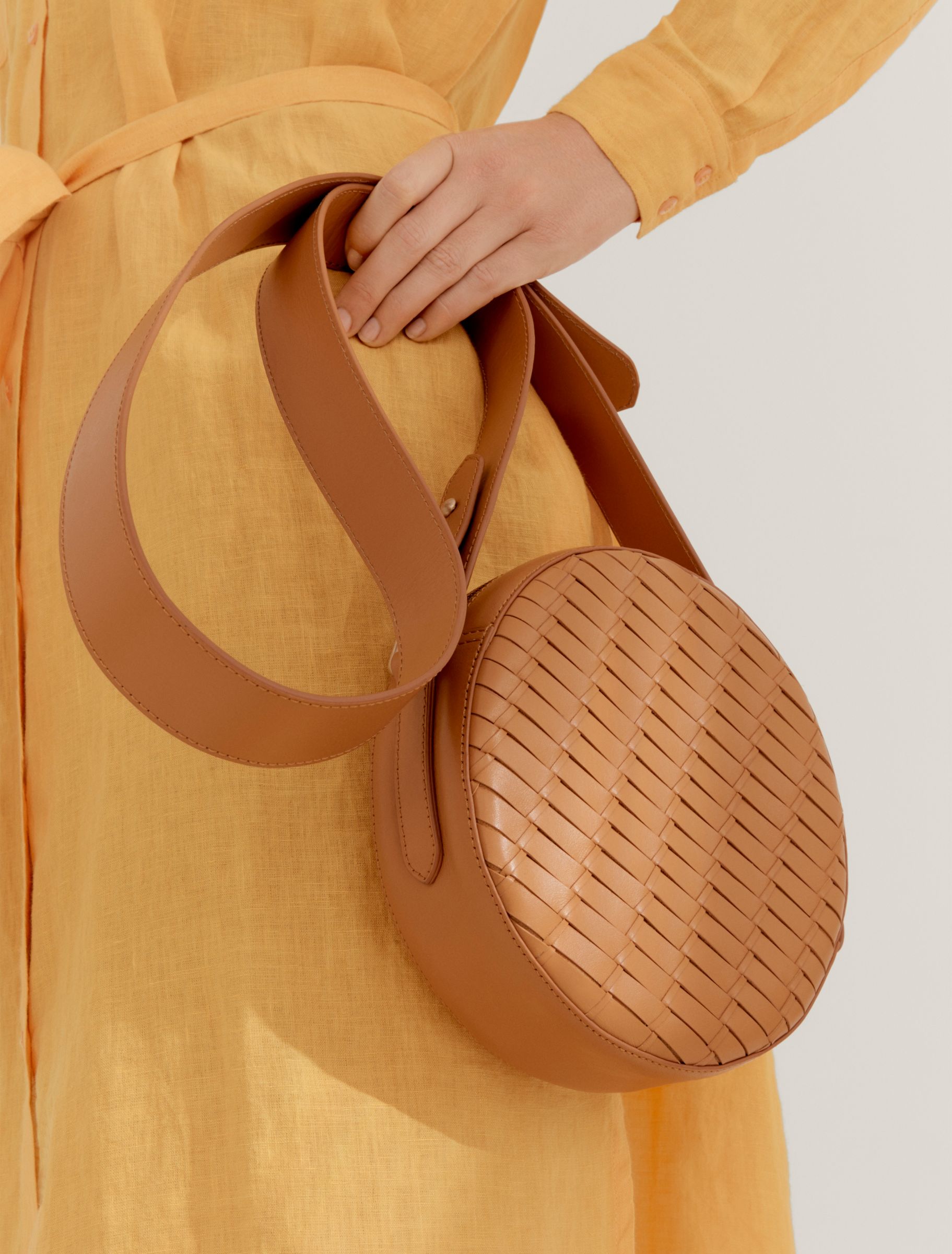 Woman carrying woven tan leather bag