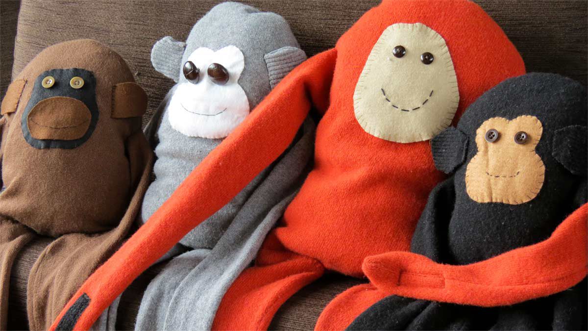 Handmade jumper monkeys lined up on a sofa